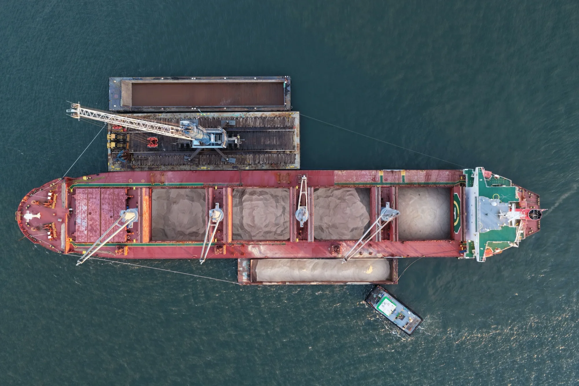 Aerial view of the ship at anchor with its holds open, full of rock salt, and barges alongside