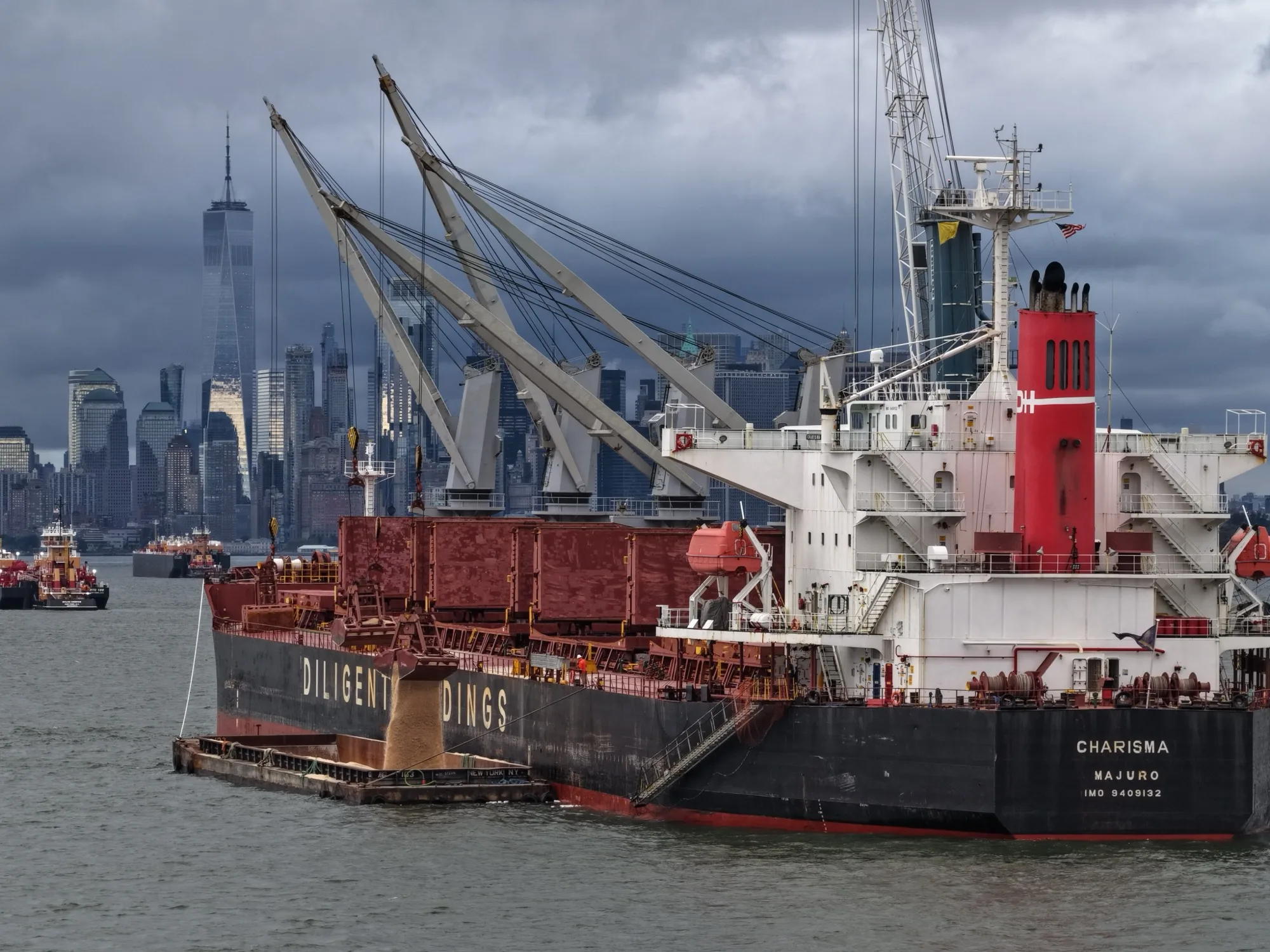 The ship at anchor off Lower Manhattan, salt pouring from the grab into a barge alongside