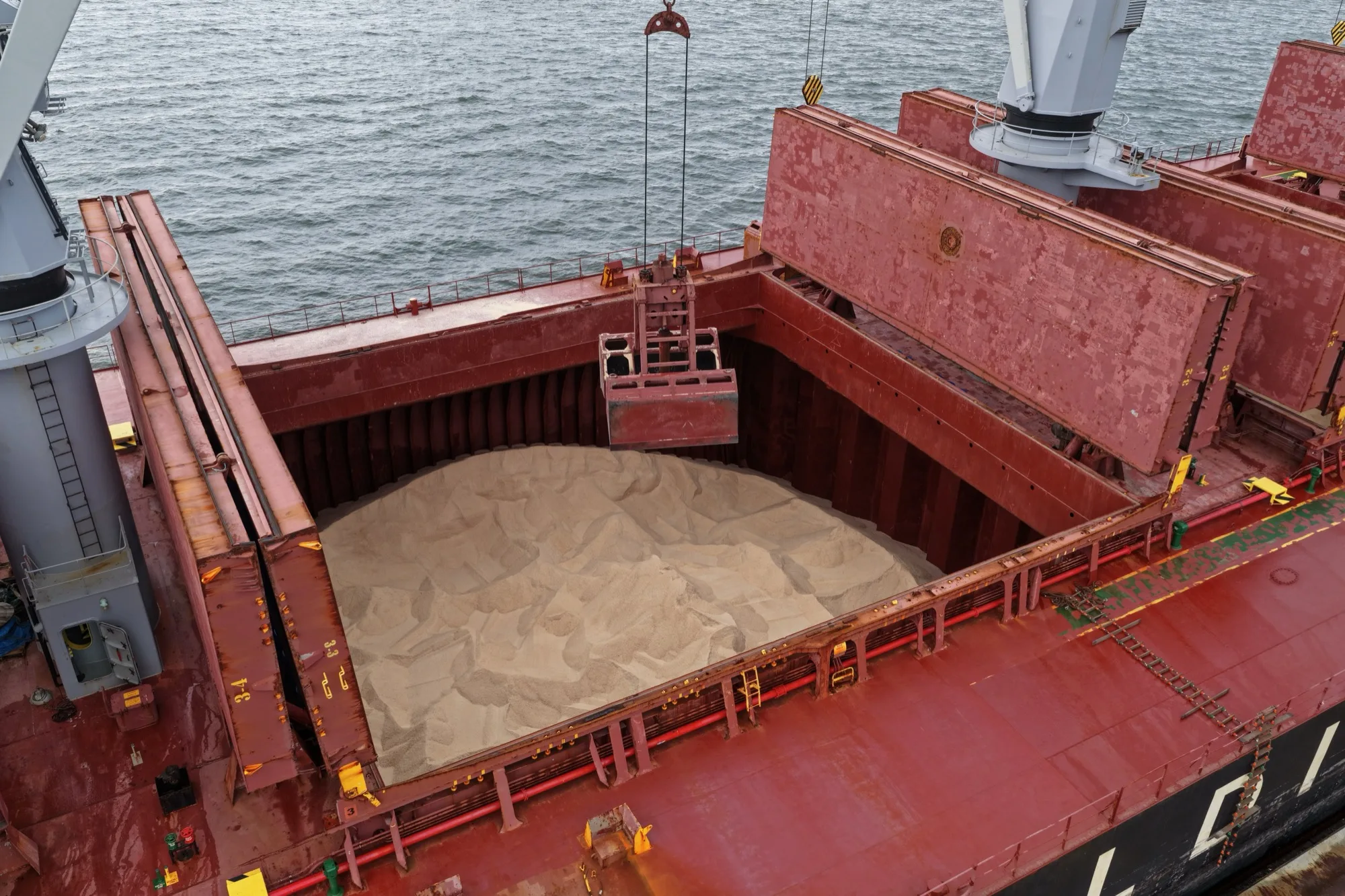 A grab lowering into an open hold full of rock salt