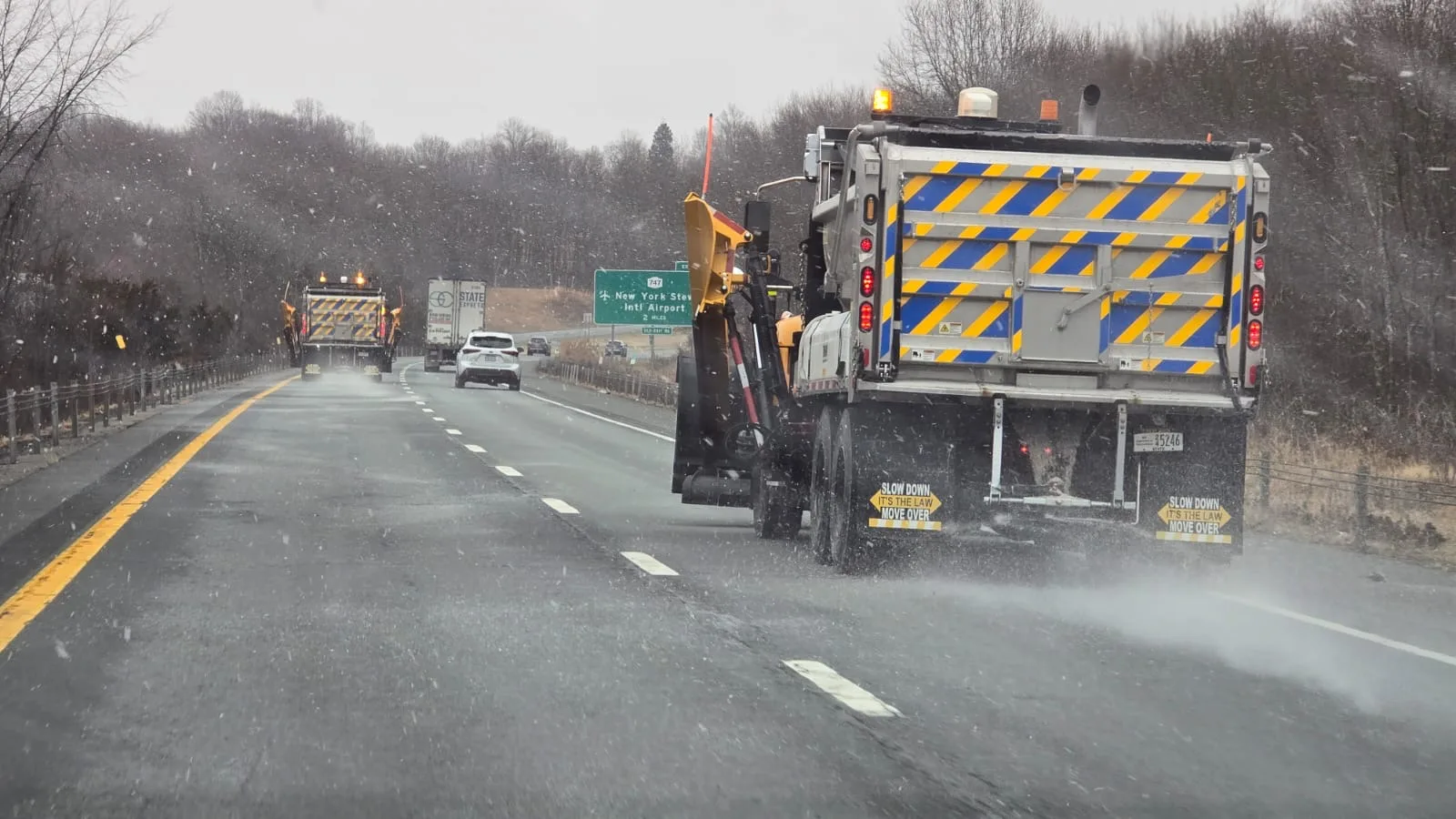 Spreader truck treating a highway in snow