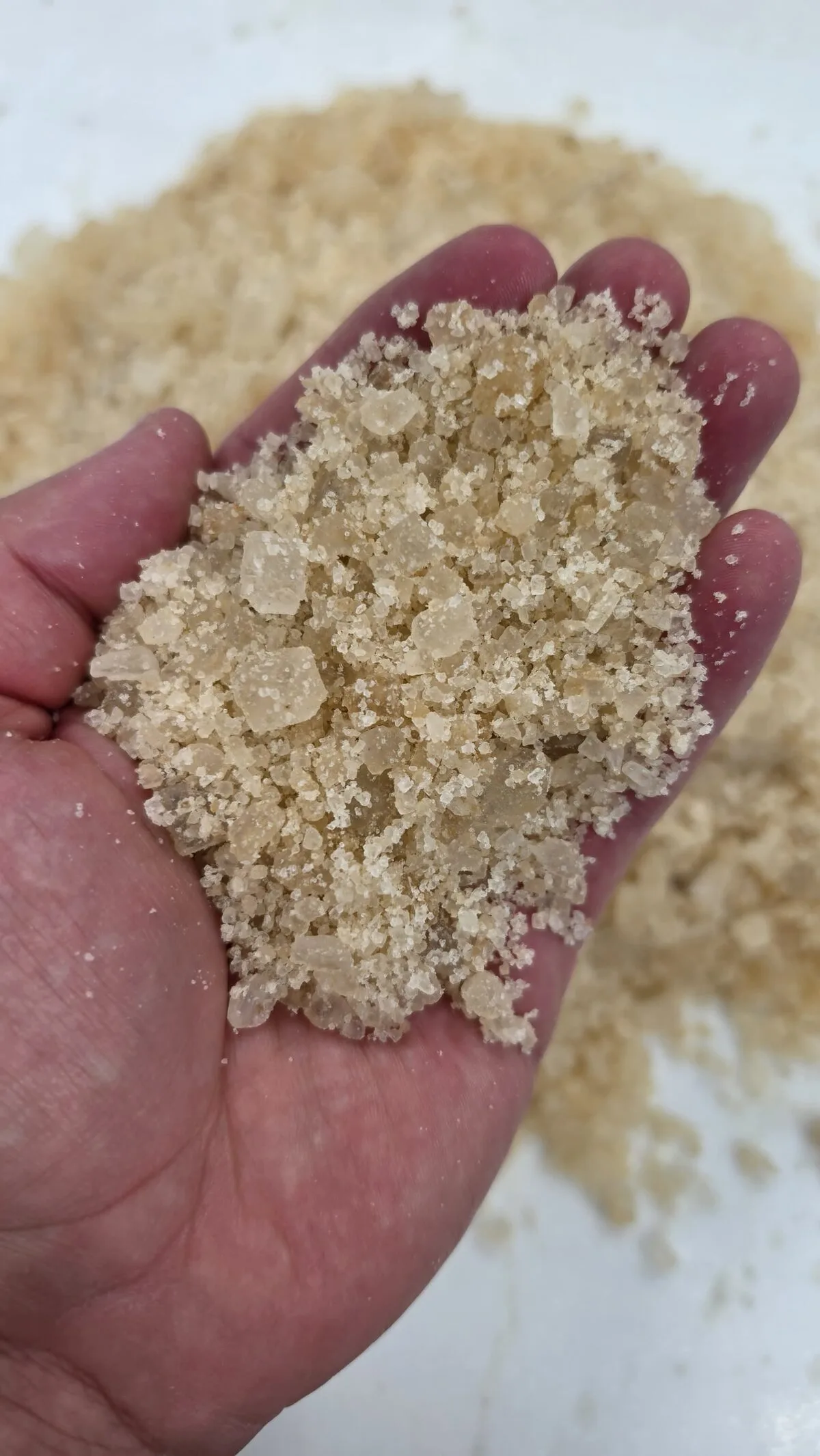 A handful of golden rock salt held over a pile