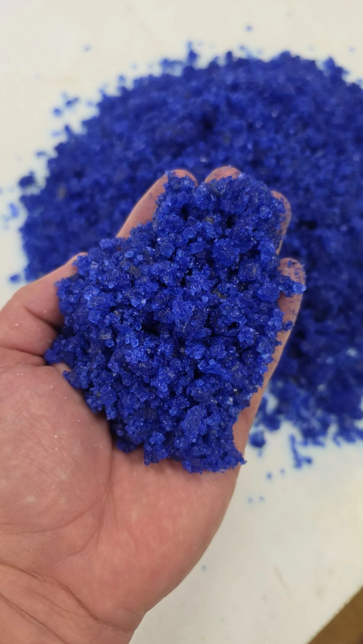 A handful of blue OnePass treated salt held over a pile