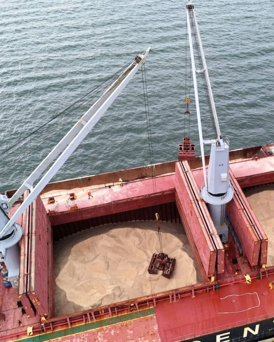 A grab in an open hold of rock salt beside one of the ship's cranes
