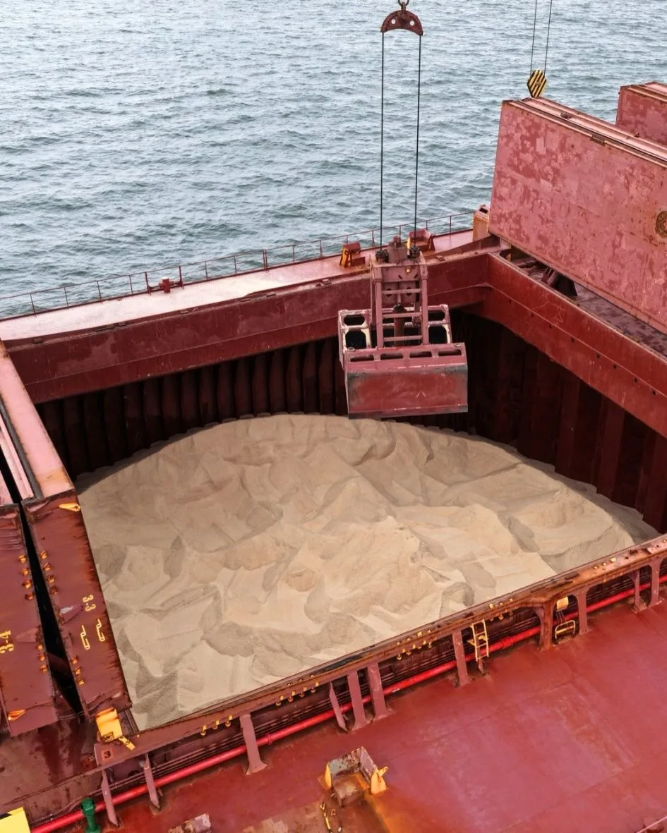 An open hold full of golden rock salt, the grab hanging above it