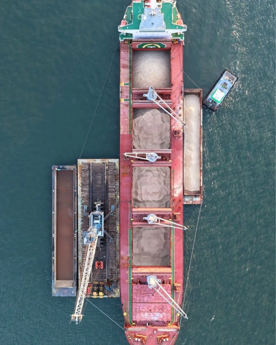 Top-down view of the ship with the crane barge and a salt barge alongside